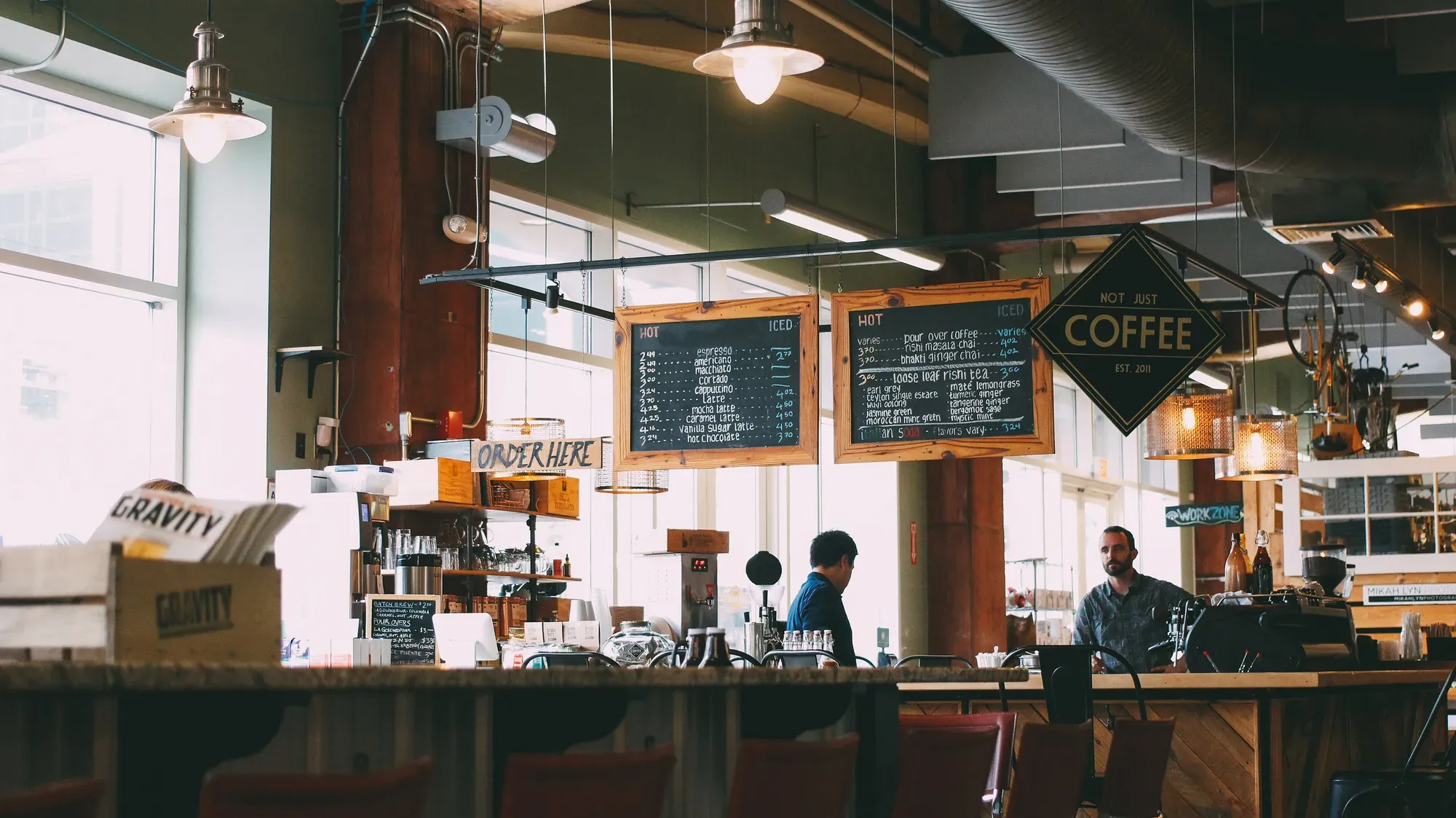 Dos personas conversando en el mostrador de una pequeña cafetería
